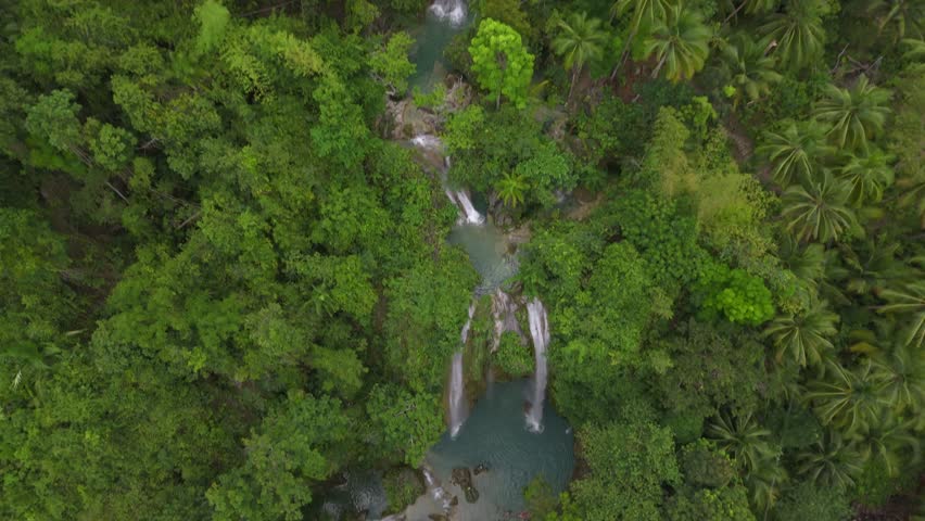 Inambakan falls aerial shot, camera descends and tilts up to reveal the face of Inambakan falls, a very large waterfall in the Philippines.