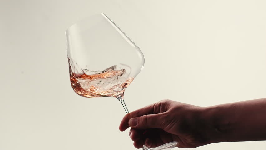 Orange or white wine bottle and glass against a sunset in a peaceful vineyard, pouring of ecological natural wine. 