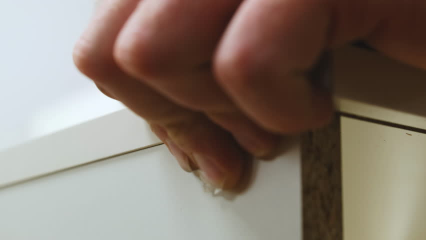 Installing upper board of shelf with wooden dowel pins in apartment closeup. Man assembles furniture carcass of plywood details working at home