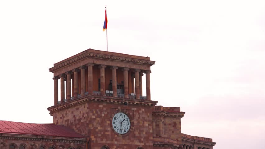  Republic square in Yerevan, Republic of Armenia. Flag of Armenia flies in Yerevan on main square of republic in center of capital. High on building against background against blue sky .