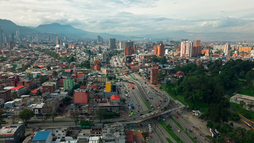 Aerial orbit establishing of the NQS avenue with variable traffic in a panoramic view of Bogota city, with a clear weather and the skyscrapers and the monserrate hill in the background.