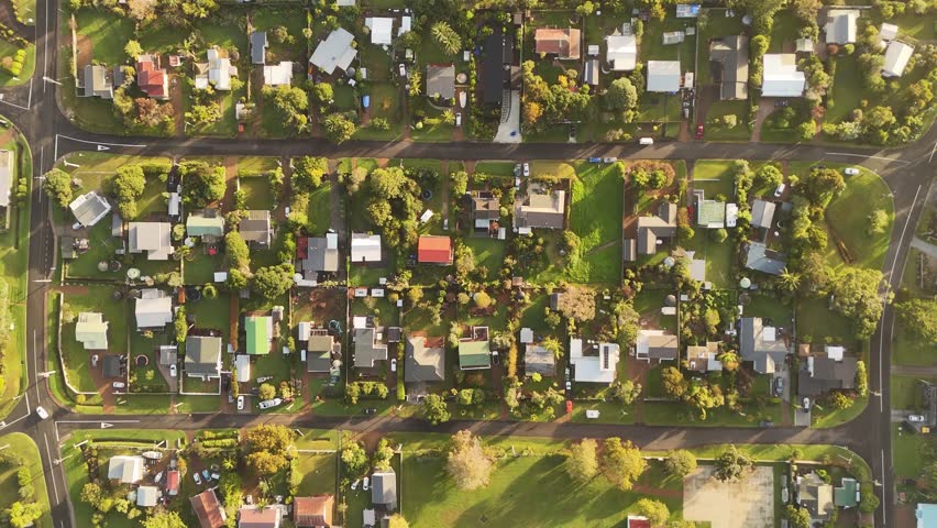 Houses in Oneroa, Waiheke Island, bathed in sunset light, New Zealand. Aerial forward directly above