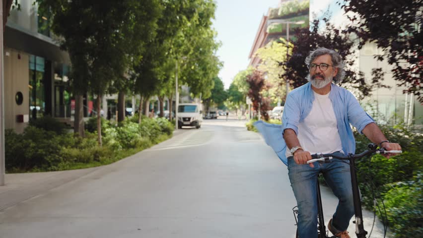 Happy active senior man doing healthy exercise riding bicycle in the city