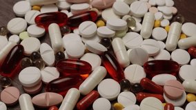 pile of assorted white round tablets, elongated capsules, and translucent softgel pills scattered across a dark wooden surface, with side lighting accentuating the contours, stamped score lines, - Powered by Shutterstock - Get 15% off with code: PIKWIZARD15