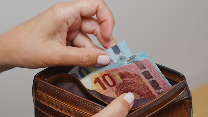 Unrecognizable woman counting euros in her wallet or purse. Counting twenty-dollar bills close-up.