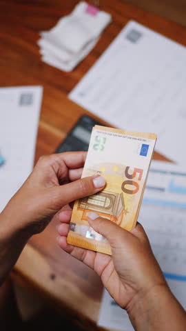 Unrecognizable woman counting fifty-dollar bills close-up. Vertical video.