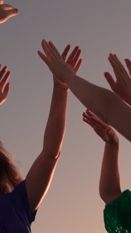 People dance to music at concert raising their hands up. Party, dancing, a group of happy people raise their hands to sky in evening. People party in nature, dancing on beach, holiday holiday outdoors