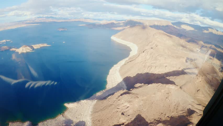Sunlit desert cliffs meet deep blue Lake Mead in epic aerial helicopter footage