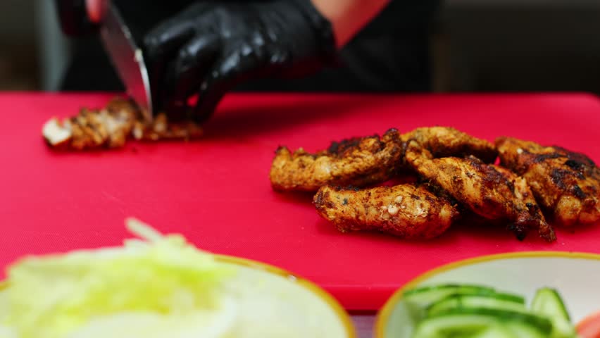 The cook cuts the fried chicken meat on a cutting board