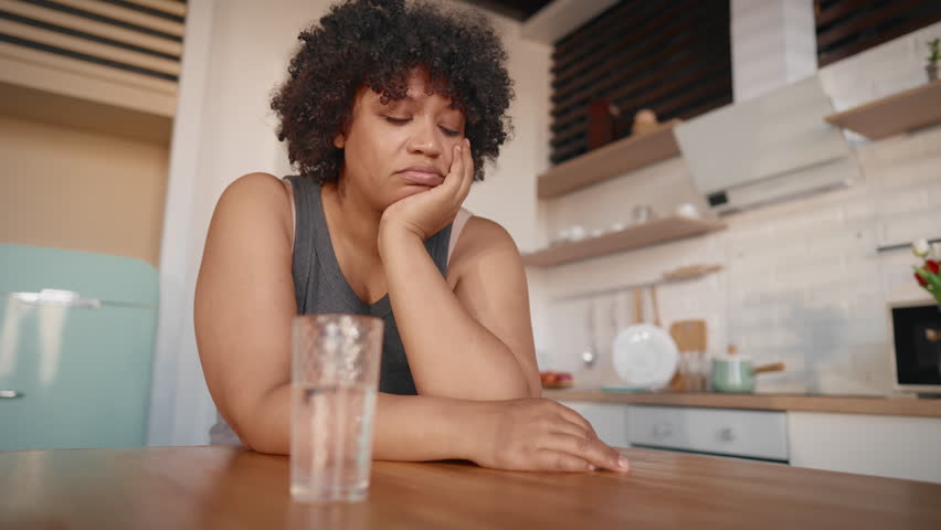 Hormonal mood swings in pregnancy, portrait of sad black woman drinking water. Unhappy depressed lady feeling sadness and boredom, overweight female person want to lose weight, diet for stay slender
