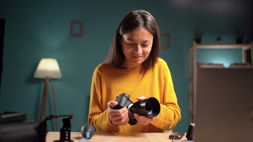 Woman photographer cleaning her camera with vacuum pump sitting on her workspace at home. blower dust.