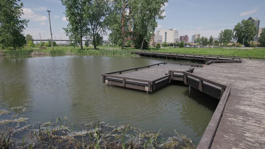 Landscape view of city public recreational park with a beautiful pond water, boardwalk, and wooden pathway and sidewalk with balcony over lake outside of Ohio downtown center in Columbus