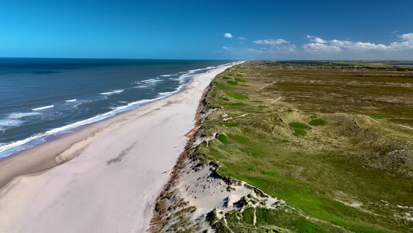 Experience the picturesque beauty of Lyngvig Lighthouse Hvide Sande beach in Jutland, Denmark, where soft golden sands meet the vibrant blue waves.