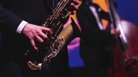 Concert view of saxophonist musician, saxophone sax player with vocalist and musical band during jazz orchestra show performing music on a scene in the stage lights, concert in a musical club hall - Powered by Shutterstock - Get 15% off with code: PIKWIZARD15