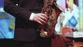 Concert view of saxophonist musician, saxophone sax player with vocalist and musical band during jazz orchestra show performing music on a scene in the stage lights, concert in a musical club hall - Powered by Shutterstock - Get 15% off with code: PIKWIZARD15