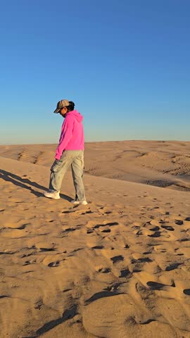 A solitary figure strolls across the expansive sand dunes of Rubjerg Knude Jutland, Denmark. The golden sands and vibrant sky create a tranquil atmosphere