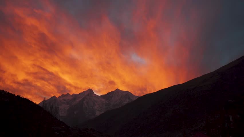 sunset over the mountains at Lahaul, Himachal Pradesh, India. Orange color clouds over mountains during evening. Sunset landscape.