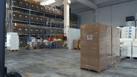 A wheeled mechanized loader uses metal forks to lift a heavy load of boxes on a wooden pallet. Loading and unloading operations in a large warehouse. Human labor on professional equipment with cargo - Powered by Shutterstock - Get 15% off with code: PIKWIZARD15