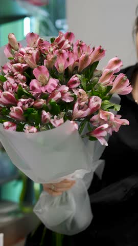 Female florist arranges delicate bouquet of pink alstroemeria flowers. Flower delivery. Small business concept