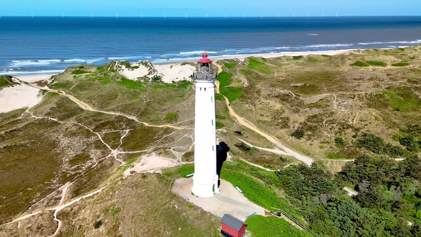 Majestic views of Lyngvig Lighthouse Hvide Sande in Jutland, Denmark, with waves crashing on the shore.