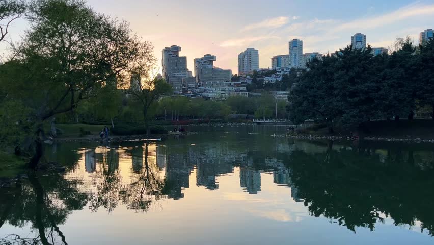 Artificial lake park and behind modern buildings silhouette at sunset in Istanbul, Turkey. (4k video)
