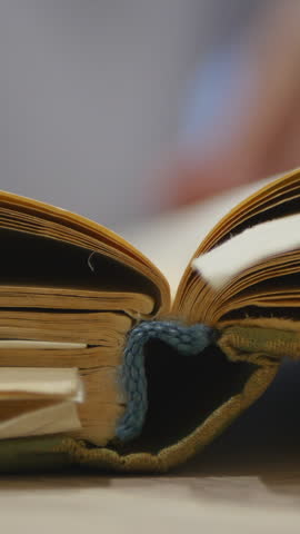 Close-Up Of Someone Flipping Through The Yellowed Pages Of An Old Book With A Woven Bookmark. Reading, Study Concept. Vertical