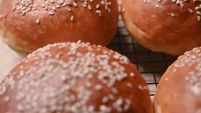 Close-up view of freshly baked golden brown burger buns with sesame seeds on a cooling rack in a cozy home kitchen setting - Powered by Shutterstock - Get 15% off with code: PIKWIZARD15