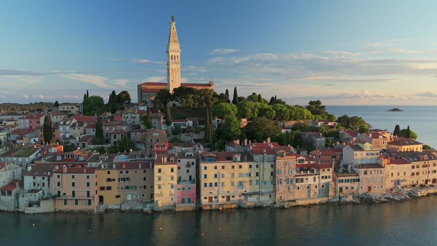 Fly near coastal town of Rovinj in Croatia during sunset. Sunset aerial shot of old town Rovinj, famous ancient Croatian city at the sea. Istria, Croatia
