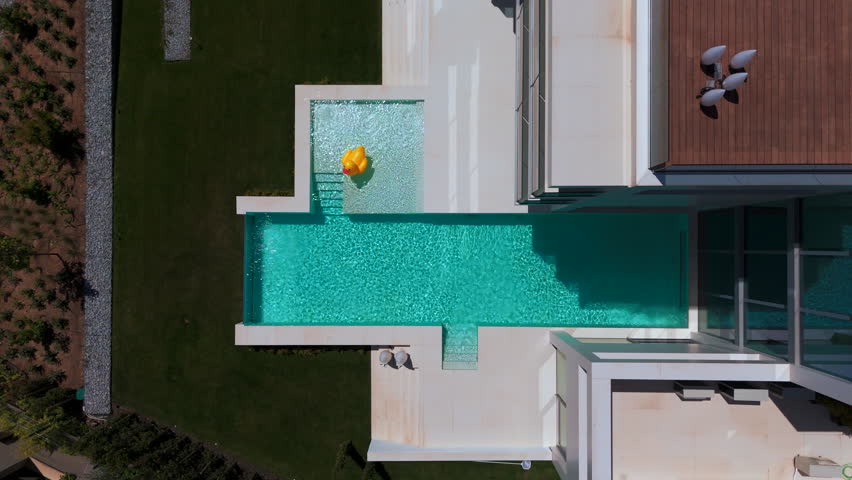 swimming pool with blue water. There is a yellow duck toy floating on the surface. Small waves are seen around the toy. The atmosphere looks calm and refreshing. High quality 4k footage