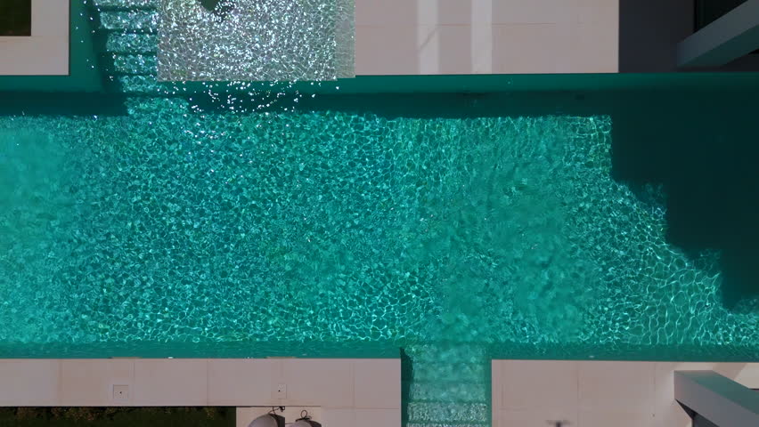 swimming pool with blue water. There is a yellow duck toy floating on the surface. Small waves are seen around the toy. The atmosphere looks calm and refreshing. High quality 4k footage