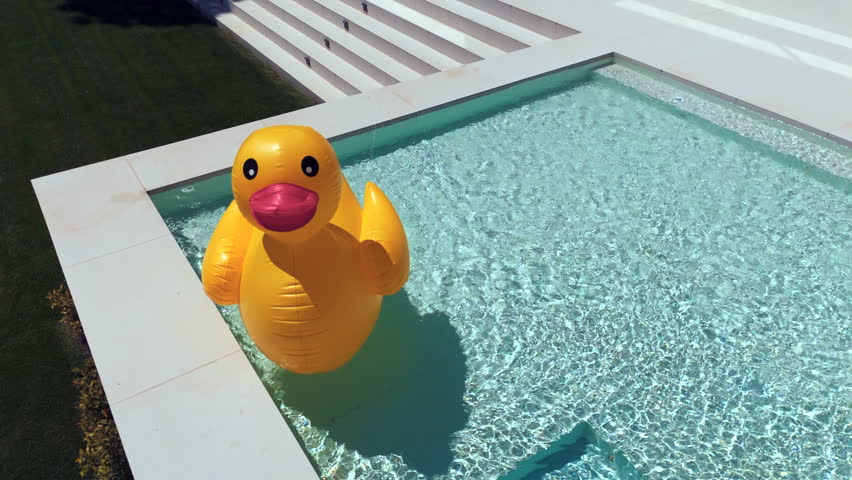 swimming pool with blue water. There is a yellow duck toy floating on the surface. Small waves are seen around the toy. The atmosphere looks calm and refreshing. High quality 4k footage