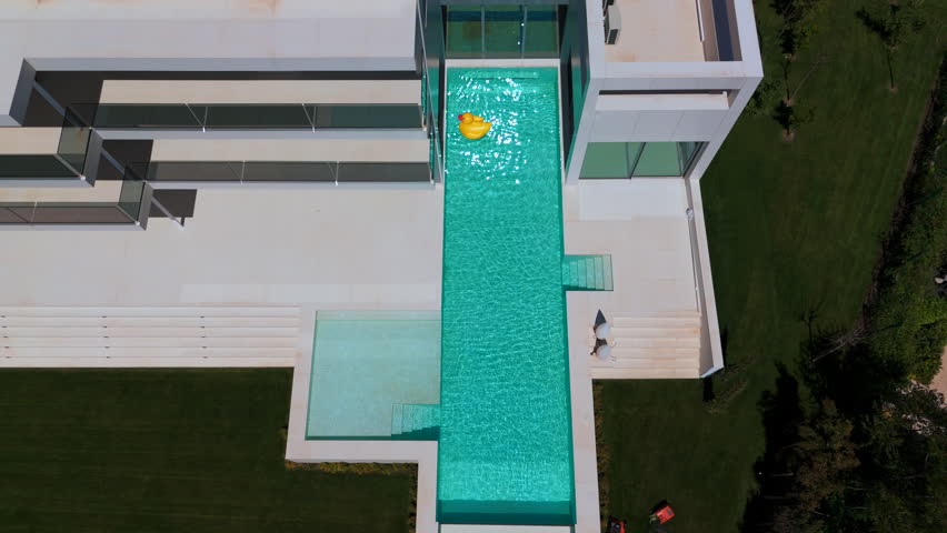 swimming pool with blue water. There is a yellow duck toy floating on the surface. Small waves are seen around the toy. The atmosphere looks calm and refreshing. High quality 4k footage
