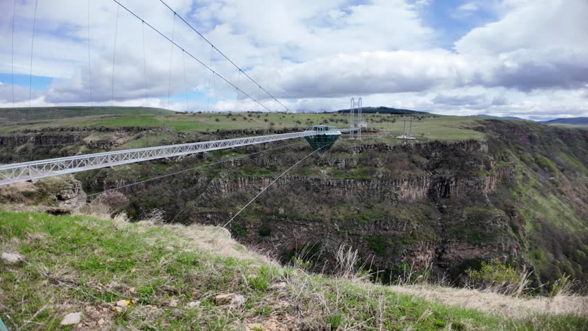 Dashbashi, Georgia - April 28,2025: Modern pedestrian suspension bridge featuring a glass diamond-shaped platform hovering over a deep canyon in Georgia