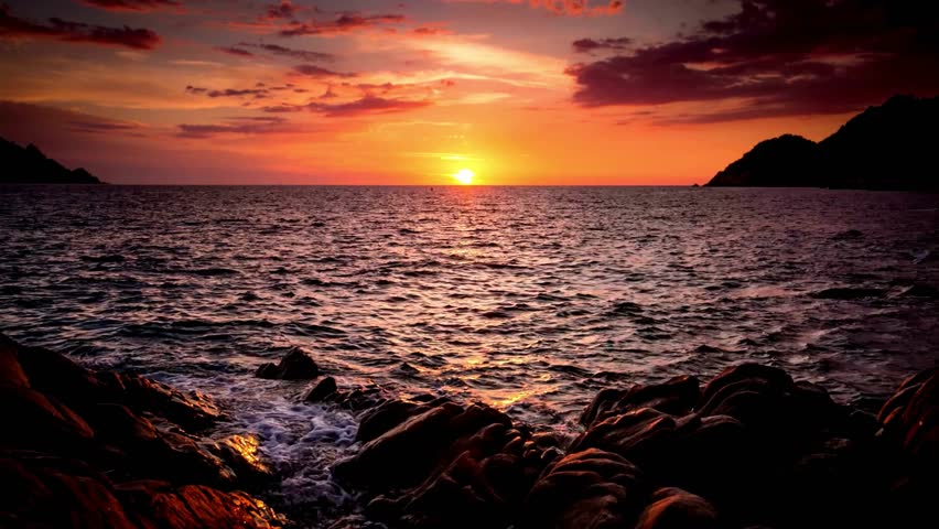 Vibrant Sunset Over Ocean with Rocky Coastline