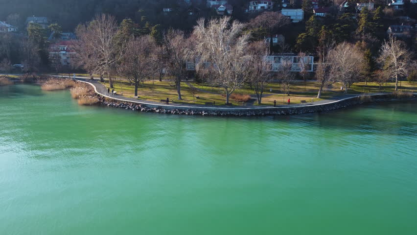 Kis Mohle pier along vivid green lake waters surrounded by trees and residential shoreline
