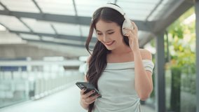 Cheerful asian woman wearing headphone and using smartphone device in the city, Female rest relax walk outside in summer day. Urban lifestyle leisure concept - Powered by Shutterstock - Get 15% off with code: PIKWIZARD15