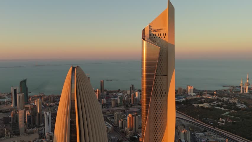 Stunning 4K aerial close-up of Al Hamra Tower and Kuwait Opera House glowing in golden hour light. Captures the coastal skyline and urban elegance of Kuwait City.
