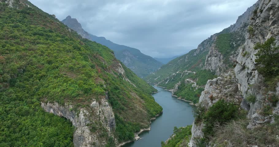 Wide rising aerial of Shala River between mountains in cloudy Albania