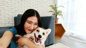Smiling young woman taking a joyful selfie while hugging her happy Corgi dog at home, showcasing the warmth, happiness, and companionship of modern pet-friendly living and lifestyle bonding. - Powered by Shutterstock - Get 15% off with code: PIKWIZARD15