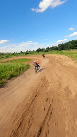 Dynamic FPV drone shot of motocross racers on dirt track. Ideal for themes of extreme sports, action, speed, adrenaline, and outdoor adventure.