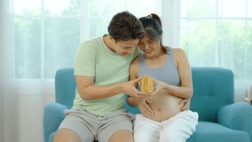 Together smiling Asian people family holding house model on hand for planning financial in the future for their baby and stable of life, Mature loving couple expecting their first baby. - Powered by Shutterstock - Get 15% off with code: PIKWIZARD15