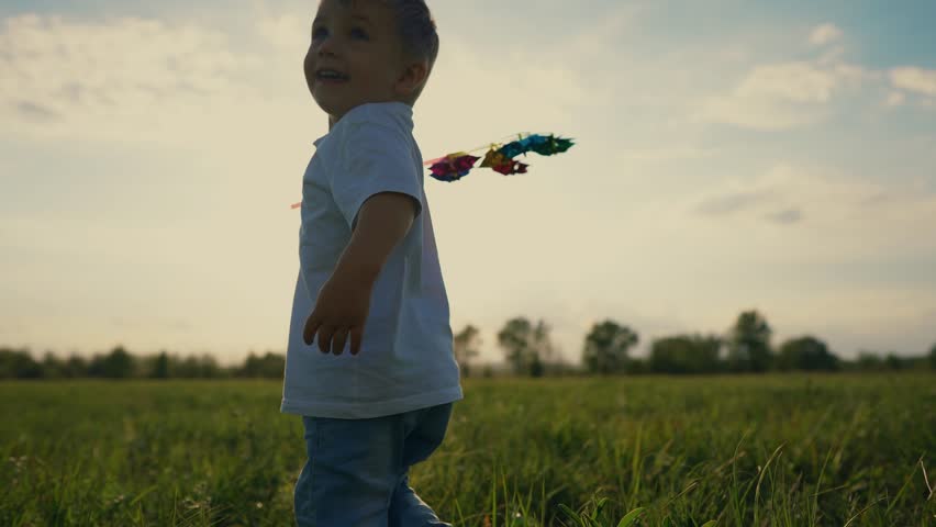 Child walking in field. Boy running on grass in a park. A child running on the grass in summer. A kid strolling through lifestyle a meadow.