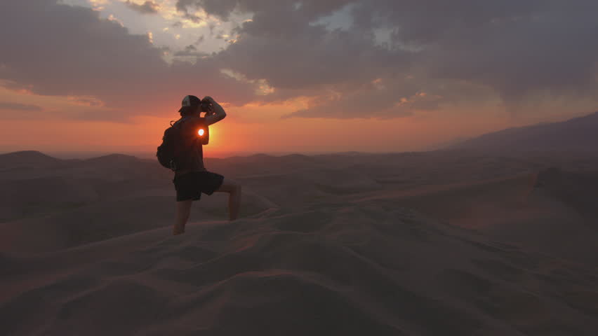 Hiker captures stunning sunset against desert landscape with silhouette photography