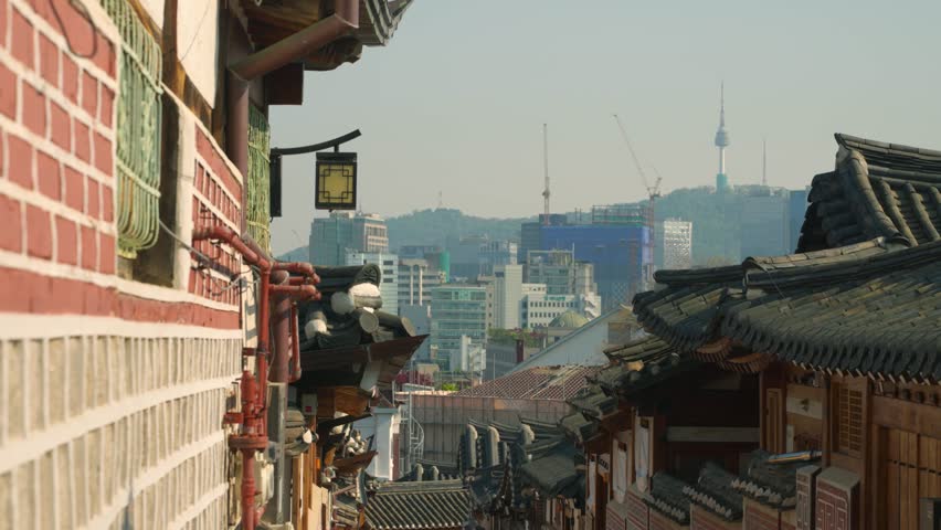 Bukchon Hanok Village, Seoul, presents a panoramic view of traditional Korean architecture, with its distinctive tiled roofs framing the distant modern cityscape and iconic N Seoul Tower - truck right