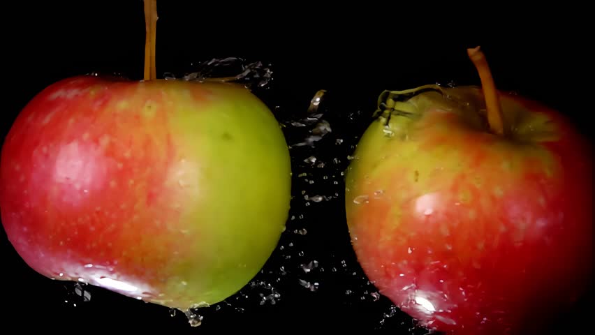 Two red apples are hitting each other on the black background and raising splashes of water in super slow motion. High quality 4k footage - Powered by Shutterstock - Get 15% off with code: PIKWIZARD15