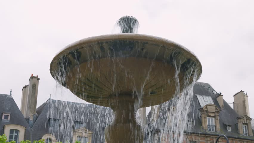 Close-up view on the one of the four Cortot fountains in the beautiful Place des Vosges in Paris, France with old historical buildings in background.