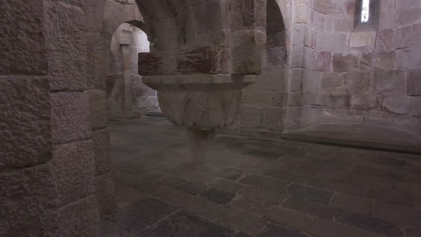 Horizontal footage moving upward from the stone floor to the vaulted ceiling inside the crypt of Leyre Monastery in Spain. The video reveals a decorated column, Romanesque arches, and a absidiole - Powered by Shutterstock - Get 15% off with code: PIKWIZARD15