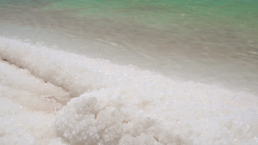 Close-up view of white salt crystals and formations on the edge of the water at the Dead Sea, Jordan.