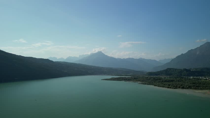 An aerial footage of the scenic Santa Croce Lake (Lago di Santa Croce) on a sunny day in the province of Belluno, Veneto, northern Italy