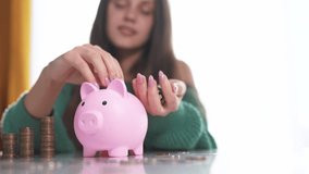 The girl smiles and puts coins in a piggy bank. Business family finance concept. A girl is saving money with lifestyle her piggy. bank. A girl is saving money with coins in a bank. - Powered by Shutterstock - Get 15% off with code: PIKWIZARD15